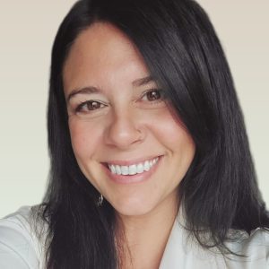 Smiling woman with long black hair and a nose ring against a pale gradient background