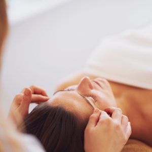 Person receiving a relaxing head massage while lying down with eyes closed in a serene spa-like setting